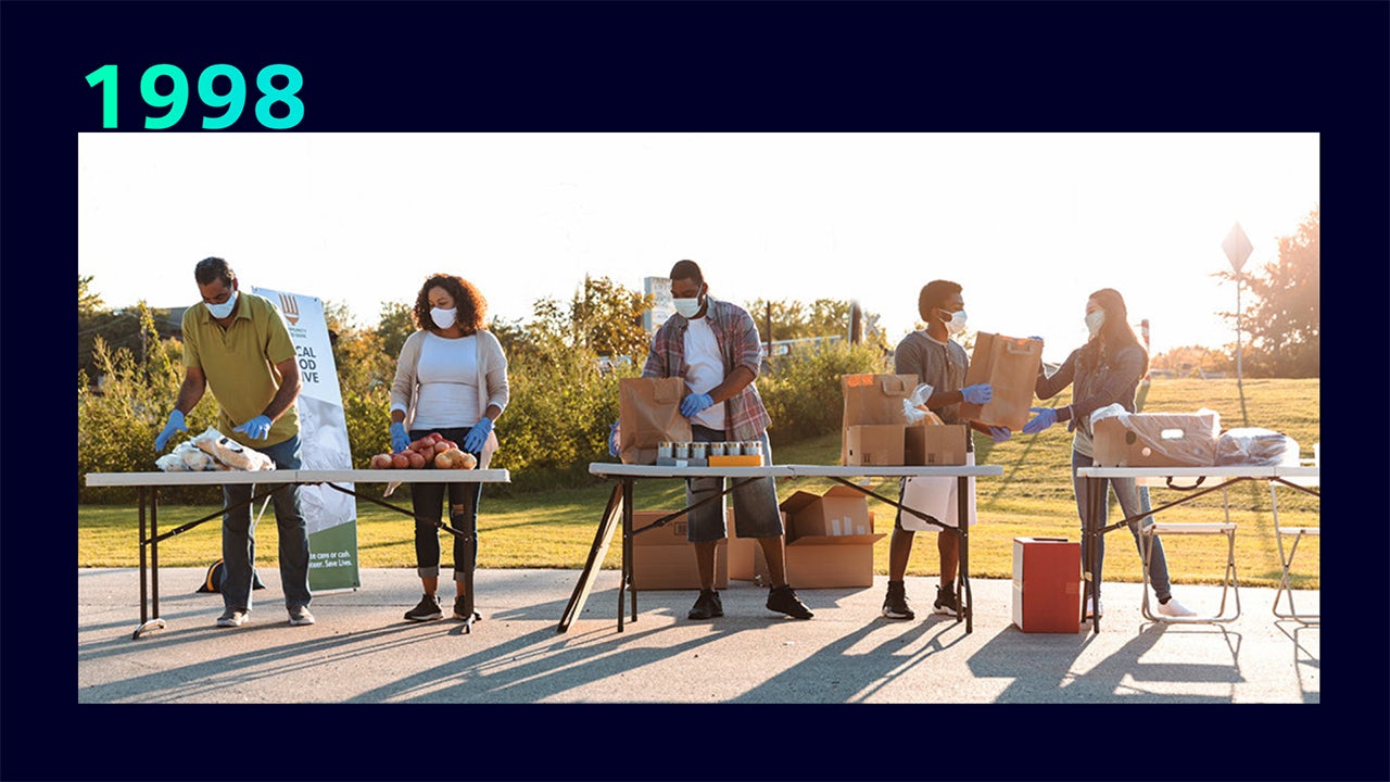 A person is standing in front of a Siemens Foundation building, holding a sign that reads 