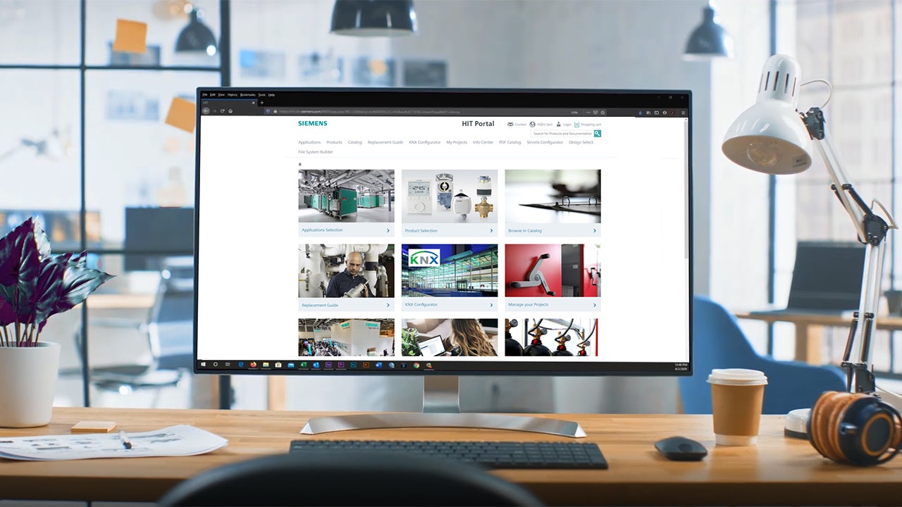 A person is standing in front of a Siemens HIT portal with a large screen and a logo on it.