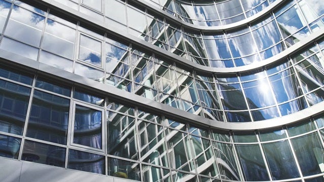 Side view of a curved building made of steel and glass.