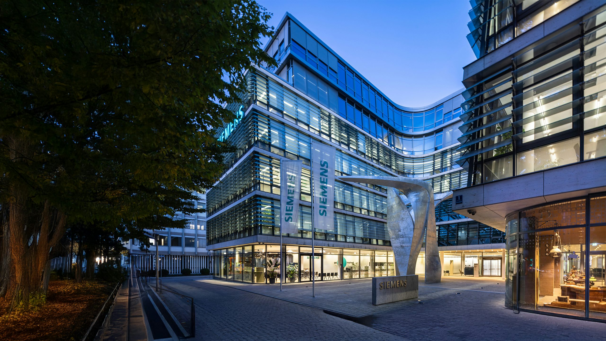 Modern glass office building with curved facade, reflecting sky and surrounding structures in its windows