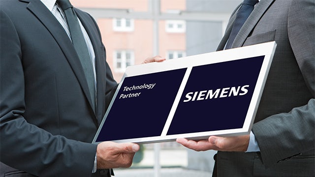 Two people holding a Siemens plaque.