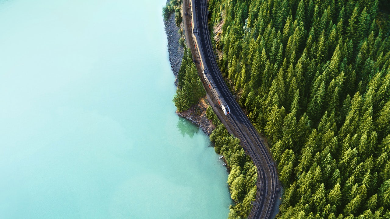 A person is standing in front of a large screen displaying a colorful abstract design.