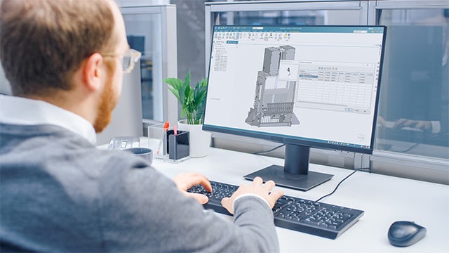 Engineer sitting behind a computer working on a grey 3D model in Solid Edge