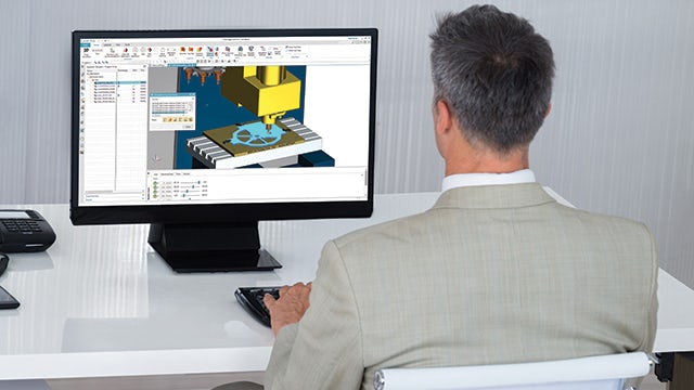 Engineer sitting behind a computer working on a CNC project in Solid Edge.