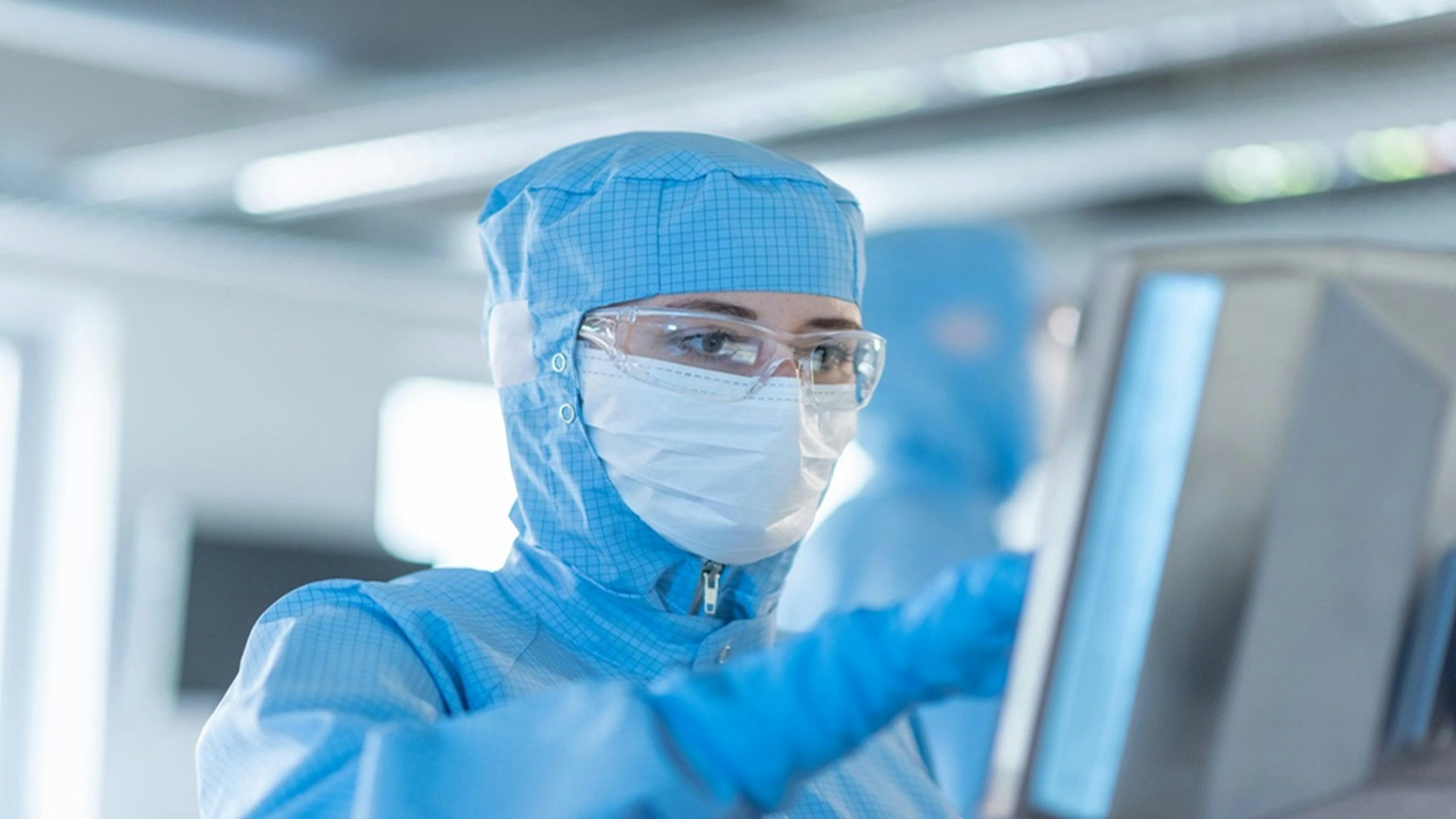 Cleanroom professional operating digital systems for pharmaceutical and biotech manufacturing.