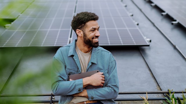 Student holding tablet in front of solar panels.