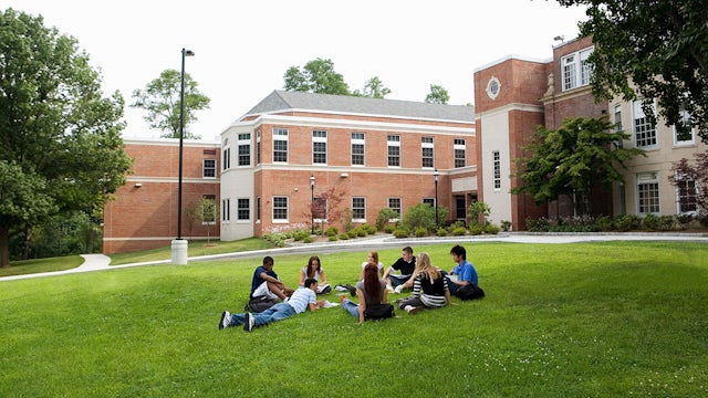 Students sitting outside on campus lawn.