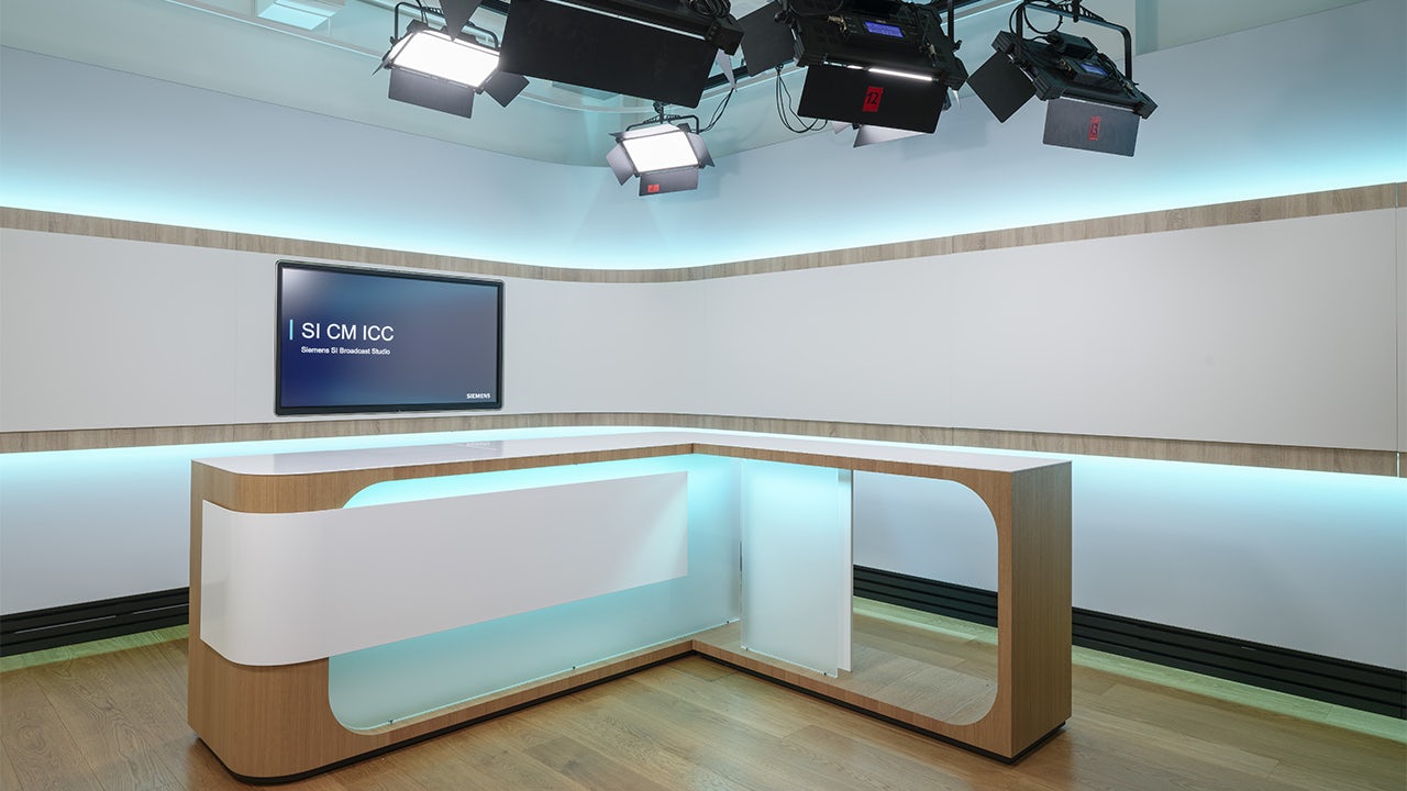 A person is standing in front of a microphone with a stand, possibly in a studio.