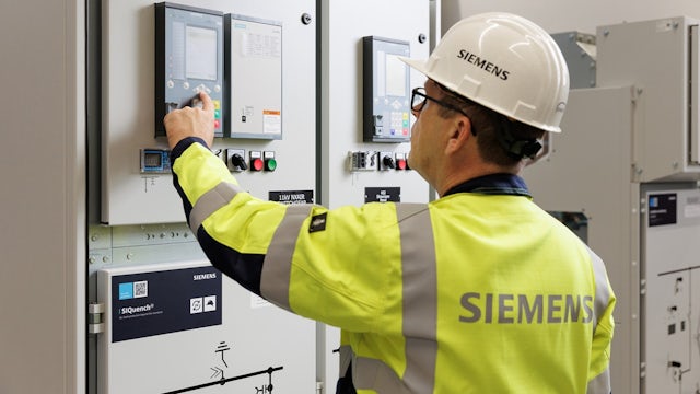 A Siemens employee adjusts some settings on a control panel.