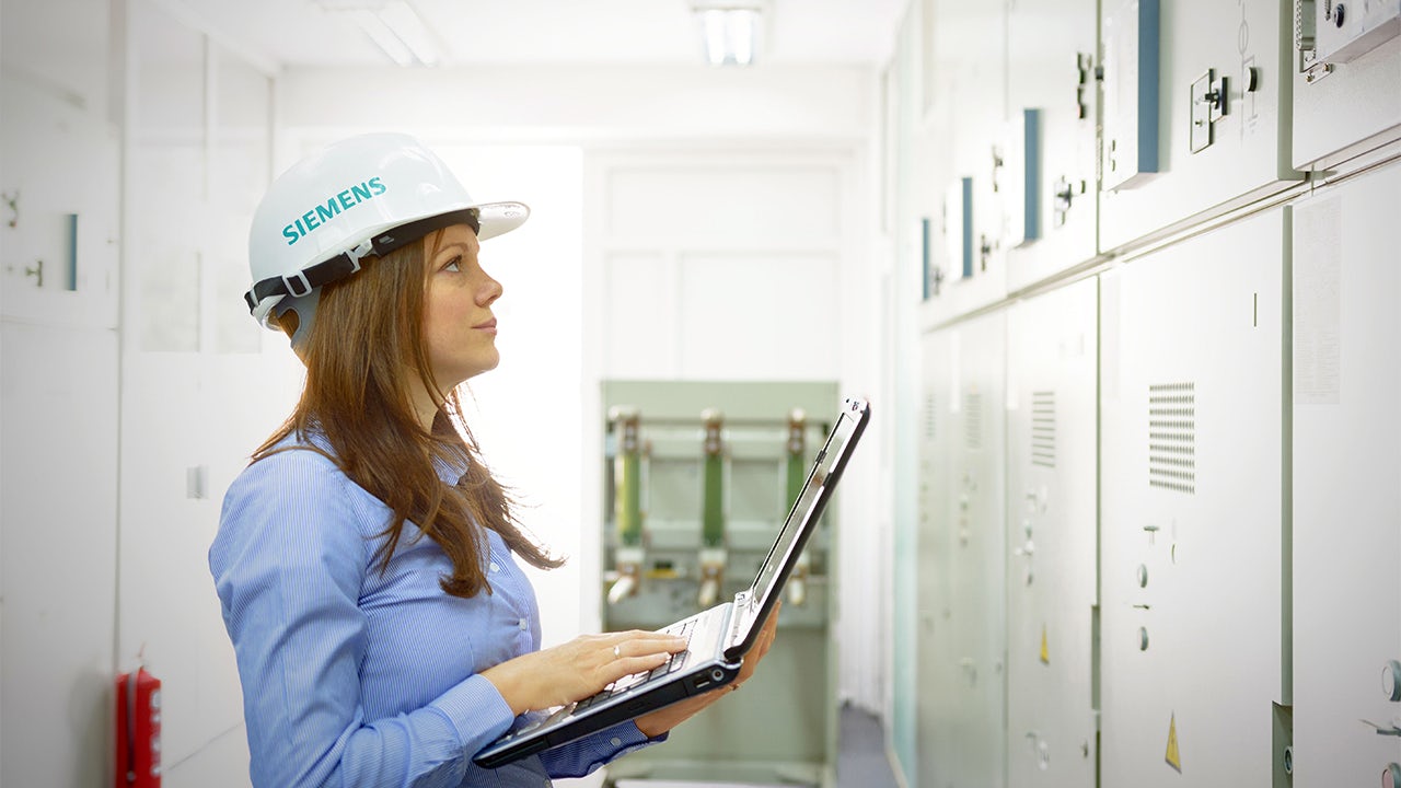 A person in a suit is standing in front of a computer screen.
