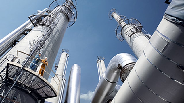 The image shows a large industrial facility with multiple tanks and pipelines, likely a tank farm or oil terminal.