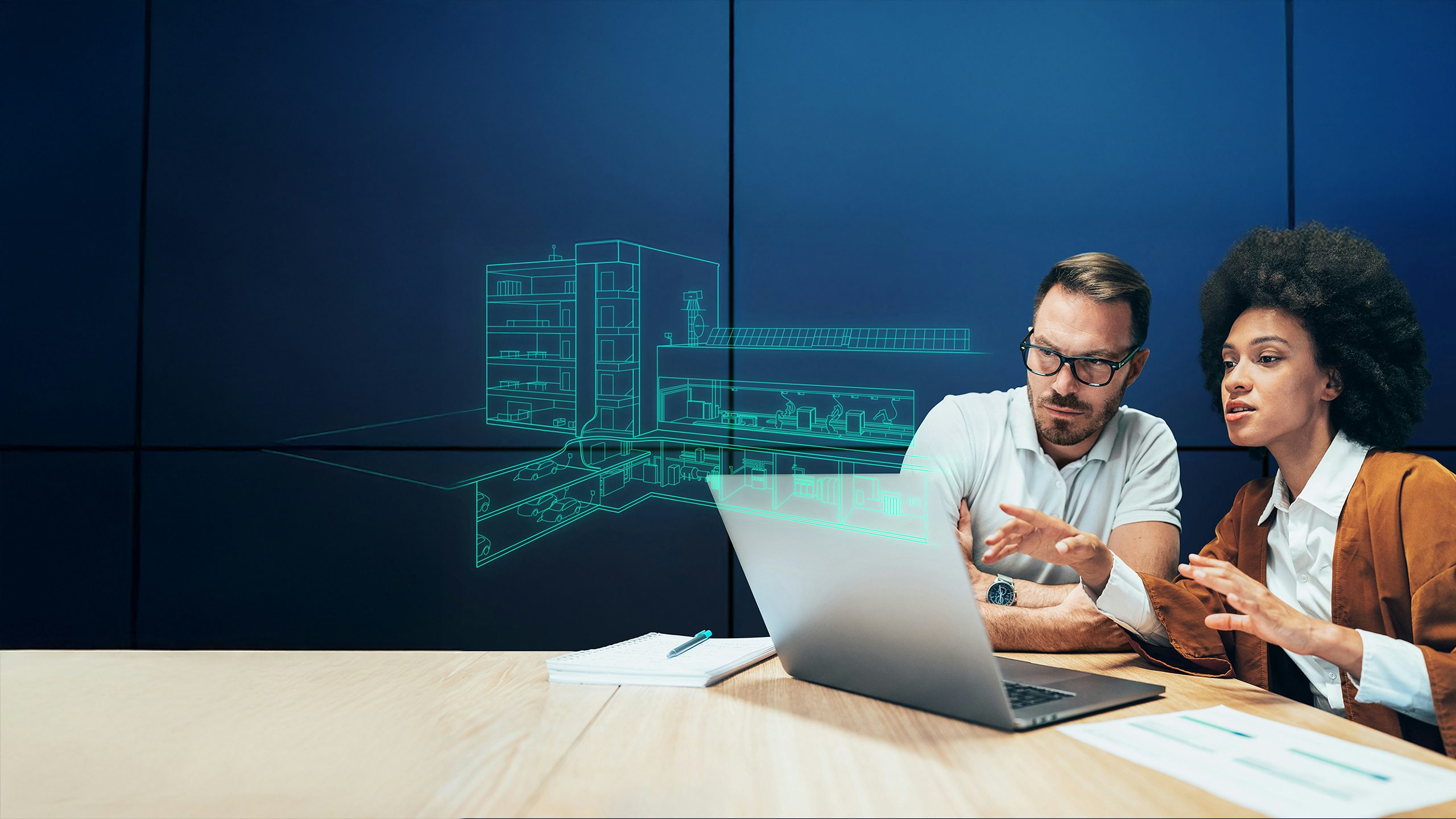 Two people are working on a computer, one typing and the other looking at the screen.