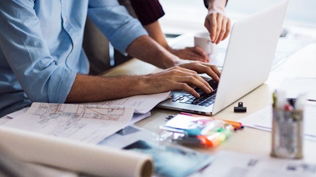 Working people on notebook with plans.