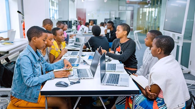A woman in a white shirt and a man in a suit are standing together in front of a building.
