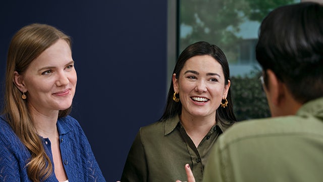 A person wearing a safety vest and a helmet is standing in front of a safety barrier.