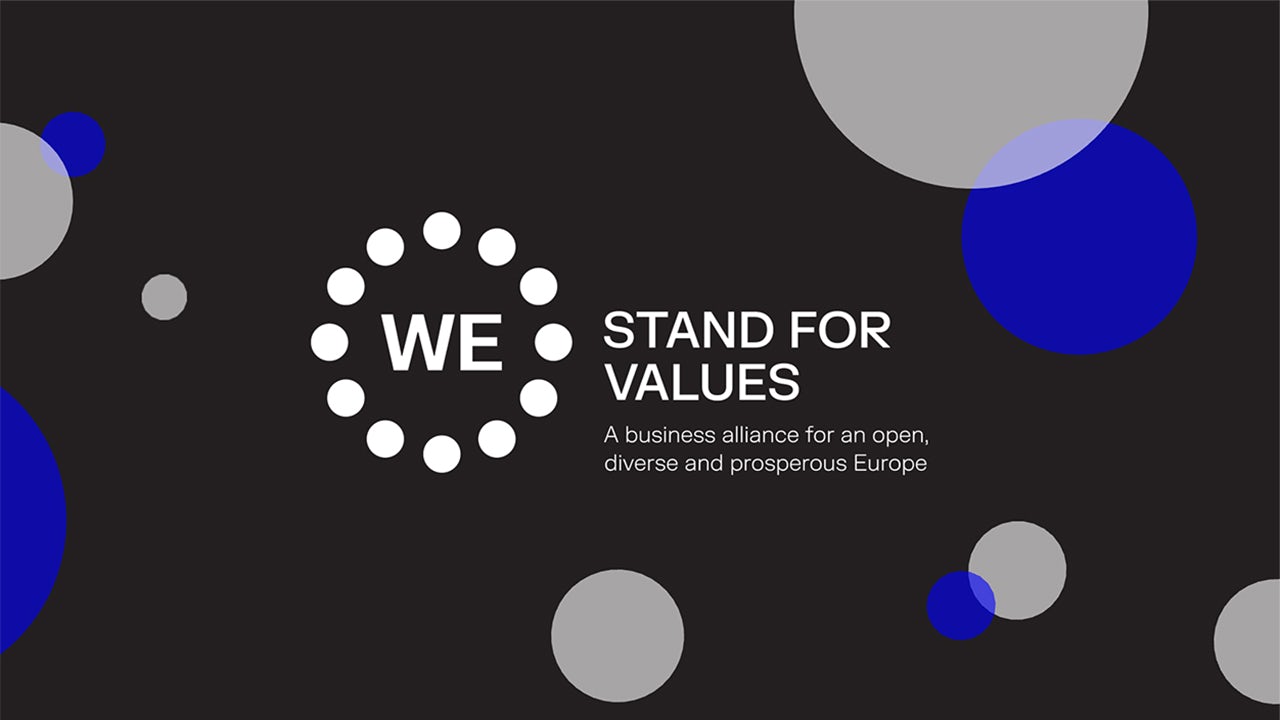 A person standing in front of a wall with a message that reads 