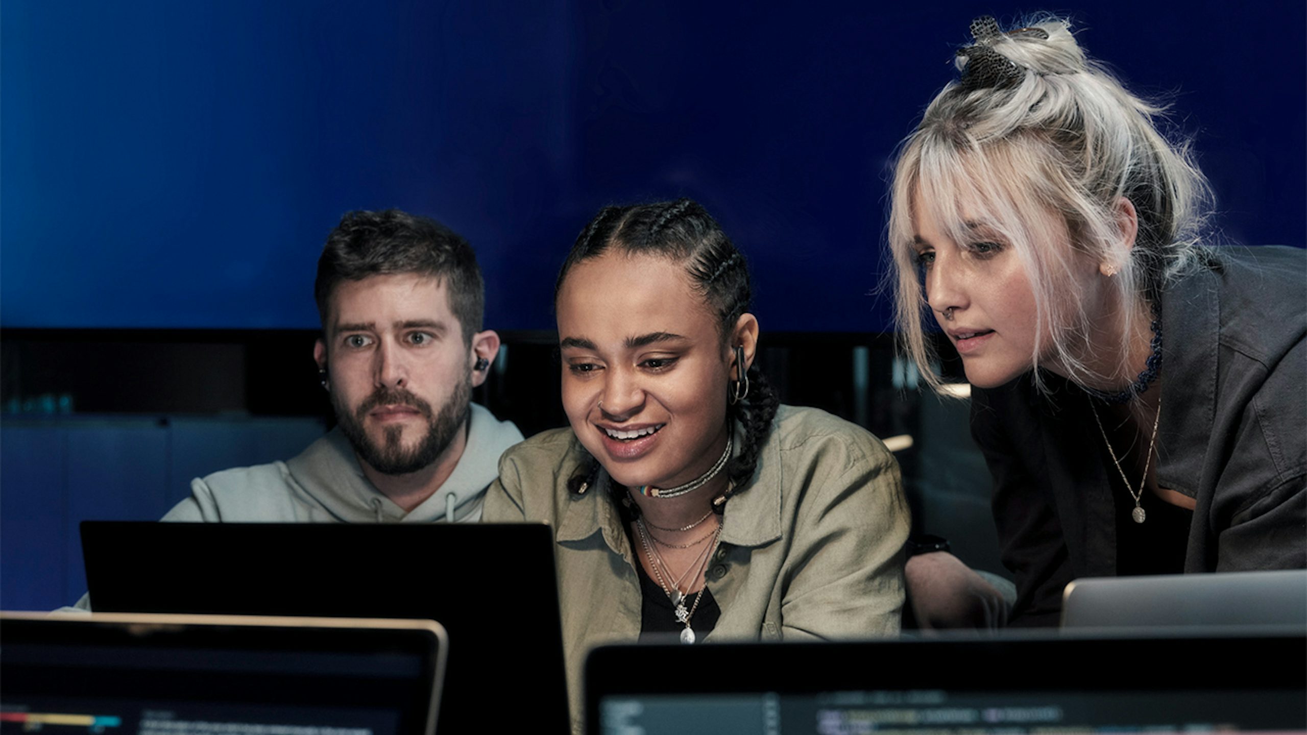 A group of diverse people sitting around a table in an office setting, engaged in discussion.